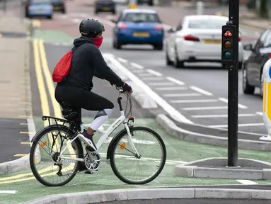Seorang wanita mengendarai sepeda di jalur sepeda persimpangan CYCLOPS (Cycle Optimized Protected Signals) di wilayah selatan Manchester, Inggris (9/10/2020). Persimpangan CYCLOPS diluncurkan dengan desain unik yang memisahkan pejalan kaki dan pesepeda dari lalu lintas. (Xinhua/Jon Super)