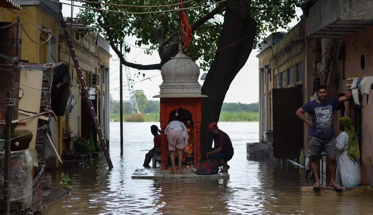 Sejumlah warga berdoa di sebuah kuil kecil saat air membanjiri perumahan dekat tepi Sungai Yamuna yang meluap di New Delhi, India, Selasa (20/8/2019). (AFP Photo/Sajjad Hussain)