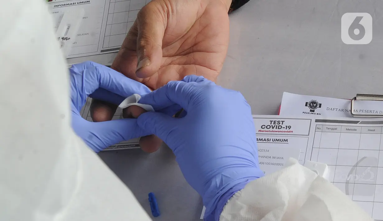 Petugas medis memeriksa warga saat rapid test oleh BIN di Lapangan Kantor Kecamatan Pamulang, Tangerang Selatan, Banten, Kamis (2/7/2020). BIN menggelar rapid test gratis terhadap 800 warga Pamulang untuk memutus mata rantai penyebaran virus corona COVID-19. (merdeka.com/Arie Basuki)