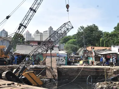 Petugas melakukan evakuasi crane jatuh di kawasan Kemayoran, Jakarta, Kamis (6/12). Crane yang digunakan untuk pembangunan turap Kali Sentiong tersebut jatuh hingga menimpa rumah warga dan menyebabkan tiga orang luka-luka. (Merdeka.com/Iqbal S. Nugroho)