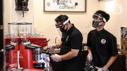 Pramusaji menggunakan pelindung wajah, masker dan sarung tangan saat menyajikan hidangan di The Atjeh Connection Coffee and Resto, Jakarta, Senin (8/6/2020). Tempat ini siap menerapkan protokol kesehatan dalam menerapkan tatanan kehidupan baru atau ‘new normal’. (Liputan6.com/Faizal Fanani)