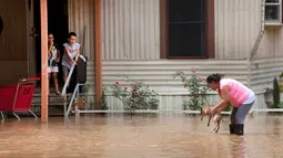 Alejandra Ventura mengangkat anjingnya dari genangan banjir yang merendam rumahnya di Richmond, Texas, Selasa (31/5). Bencana banjir terjadi lantaran Sungai Brazos meluap akibat hujan deras yang mengguyur wilayah tersebut. (REUTERS/Daniel Kramer)
