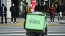 Orang-orang mengenakan masker untuk mencegah penyebaran virus corona menunggu lampu lalu lintas di persimpangan di Tokyo (8/2/2021). Ibukota Jepang mengonfirmasi lebih dari 270 kasus virus korona baru pada hari Senin. (AP Photo/Eugene Hoshiko)