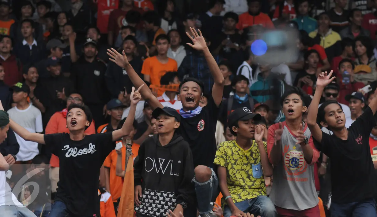 Suporter tim Macan Kemayoran meneriakkan yel yel saat menyaksikan laga uji coba antara Persija melawan Barito Putera di Stadion Bea Cukai Rawamangun, Jakarta, Selasa (5/4/2016). Laga uji coba berakhir imbang 2-2. (Liputan6.com/Helmi Fithriansyah)