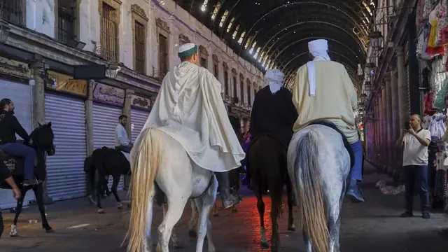 Jemaah haji, termasuk tiga orang dari Spanyol, berpose dengan kuda mereka di luar Pasar al-Hamidiyah di Damaskus, Suriah, 21 April 2025, selama perjalanan berkuda dari Spanyol ke Arab Saudi untuk ibadah haji. (AP/Omar Albam)