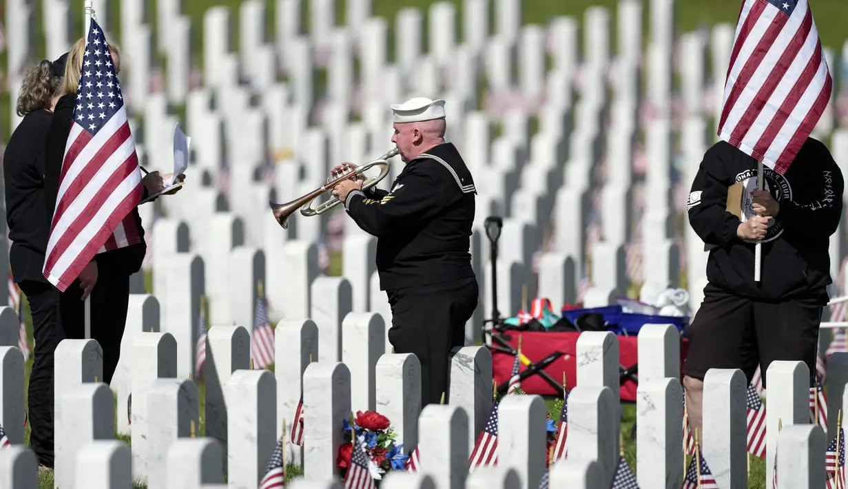 Pensiunan Angkatan Laut Amerika Serikat Yeoman Mark Stallins memainkan Taps untuk keluarga prajurit yang gugur di sebuah kuburan di Pemakaman Nasional Fort Logan, Sheridan, Colorado, Amerika Serikat, 30 Mei 2022. (AP Photo/David Zalubowski)