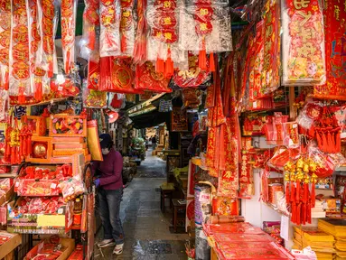 Seorang vendor menunggu pelanggan di kiosnya yang menjual dekorasi di Hong Kong (15/1/2021). Menjelang Tahun Baru Imlek, tahun ini menandai Tahun Sapi, yang jatuh pada 12 Februari. (AFP/Anthony Wallace)