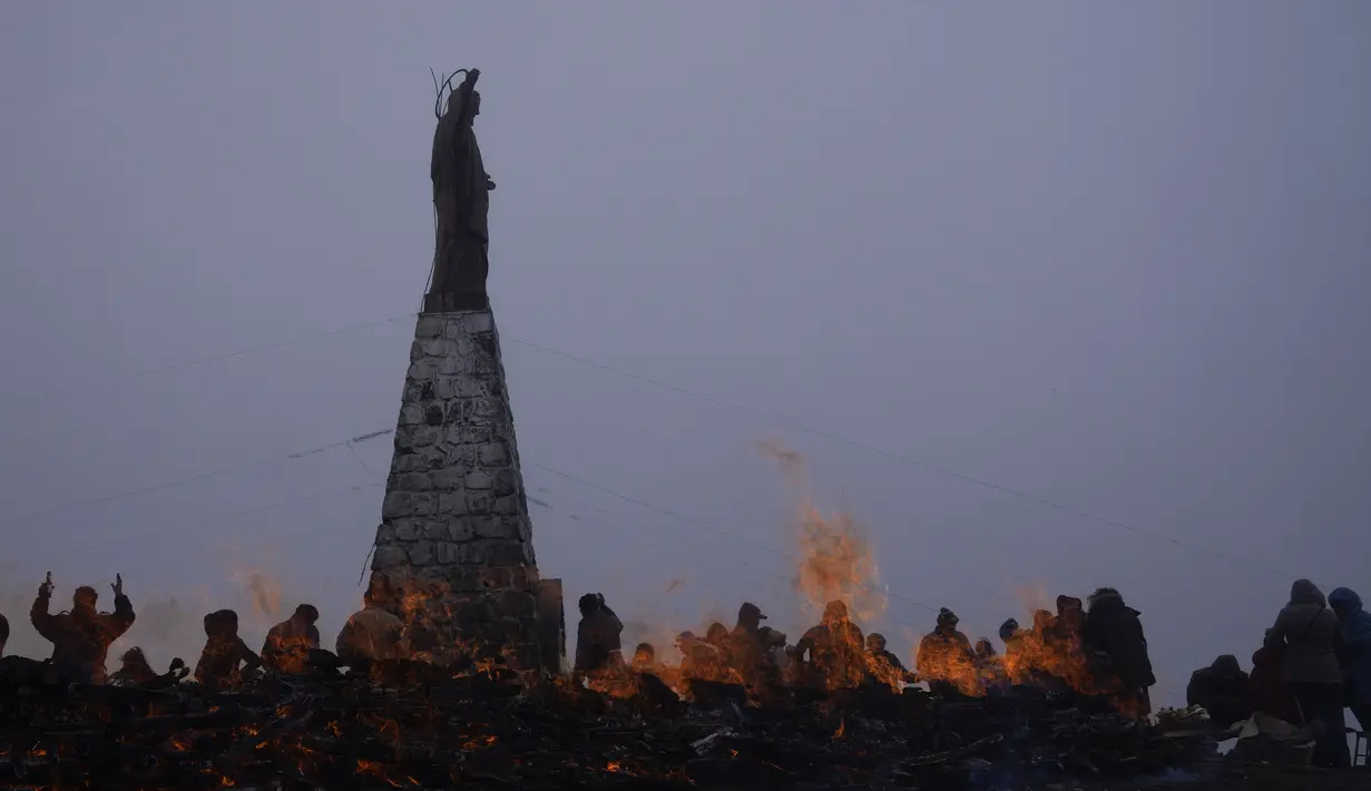 Orang-orang membakar persembahan untuk menghormati Pachamama atau Ibu Pertiwi di La Cumbre, sebuah gunung yang dianggap suci tempat patung Yesus Kristus berdiri di pinggiran La Paz, Bolivia, Minggu (1/8/2021). (AP Photo/Juan Karita)