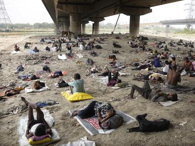 Para tunawisma tidur di bawah naungan jembatan layang pada hari yang panas di New Delhi, Jumat (20/5/2022). Ibu kota India dan sekitarnya tengah menghadapi kondisi gelombang panas yang ekstrem. (AP Photo/Manish Swarup)