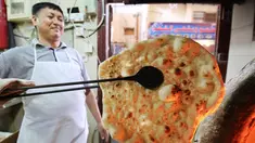 Tukang roti memanggang roti Iran atau taftoon di sebuah toko di Kuwait City, Kuwait, 27 Juni 2019. Taftoon telah menjadi makanan pokok di Kuwait selama beberapa dekade. (YASSER AL-ZAYYAT/AFP)