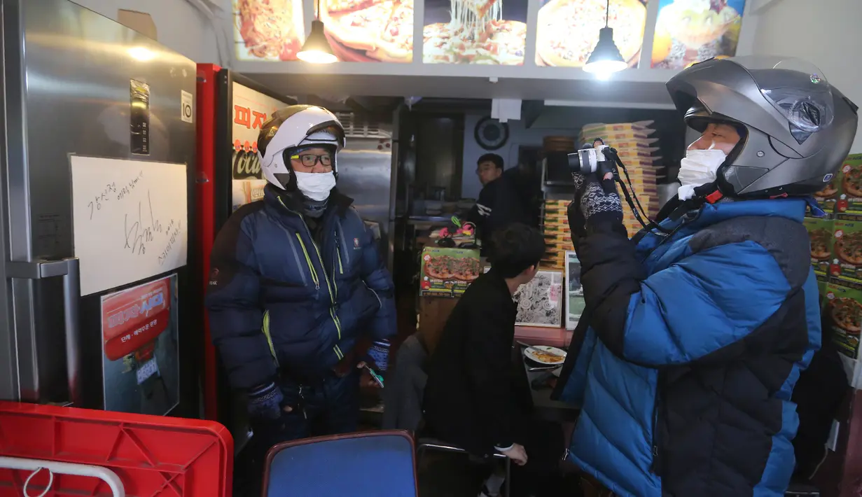 Pengunjung berfoto di sebelah kertas dengan tanda tangan sutradara Bong Joon-ho di restoran pizza yang muncul dalam film'Parasite' di Seoul, 15 Februari 2020. Lokasi syuting Parasite di Korea Selatan semakin ramai dikunjungi turis setelah film itu memborong Piala Oscar 2020. (AP/Ahn Young-joon)