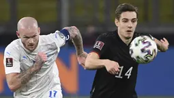 Gelandang Islandia Aron Gunnarsson (kiri) dan gelandang Jerman Florian Neuhaus bersaing memperebutkan bola pada pertandingan kualifikasi Piala Dunia 2022 Zona Eropa Grup J di Duisburg, Jumat (26/3/2021) dinihari WIB. Jerman berhasil melumat Islandia dengan skor 3-0. (Ina Fassbender/AFP)