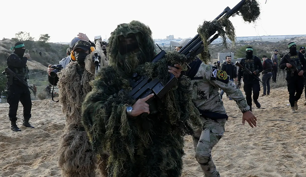 Militan Palestina mengenakan busana penyamaran dan memegang senjata mereka selama latihan militer yang diselenggarakan oleh faksi militer di Rafah, Jalur Gaza selatan, Rabu (29/12/2021). (AP Photo/Adel Hana)