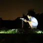 Rizki, 27 tahun, warga Kota Bangkalan, tengah mengamati gerhana bulan total lewat lensa kamera di puncak Bukit Jaddih. (Liputan6.com/Musthofa Aldo)