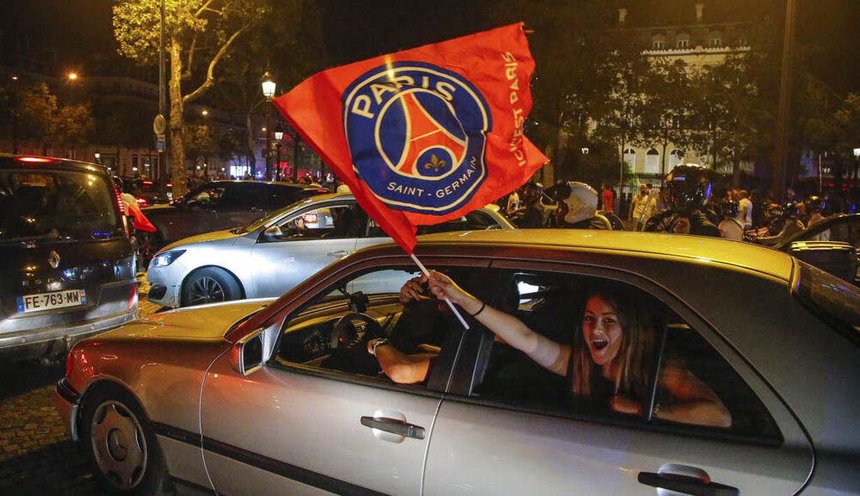Seorang suporter mengibarkan bendera Paris Saint Germain (PSG) saat merayakan keberhasilan lolos ke final Liga Champions di Paris, Rabu (19/8/2020). Berkat kemenangan atas RB Leipzig, PSG untuk pertama kalinya berhasil lolos ke final Liga Champions. (AP/Michel Euler)
