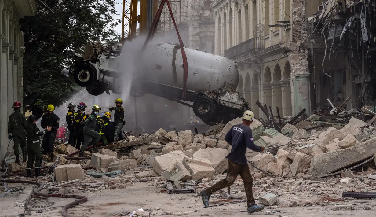 <p>Petugas pemadam kebakaran menyemprot truk tangki dengan air untuk mendinginkannya saat mereka memindahkannya dari lokasi ledakan mematikan yang menghancurkan Hotel Saratoga di Havana, Kuba, 6 Mei 2022. Ledakan kuat yang diduga disebabkan oleh kebocoran gas alam menewaskan 18 orang dan melukai puluhan orang. (AP Photo/Ramon Espinosa)</p>