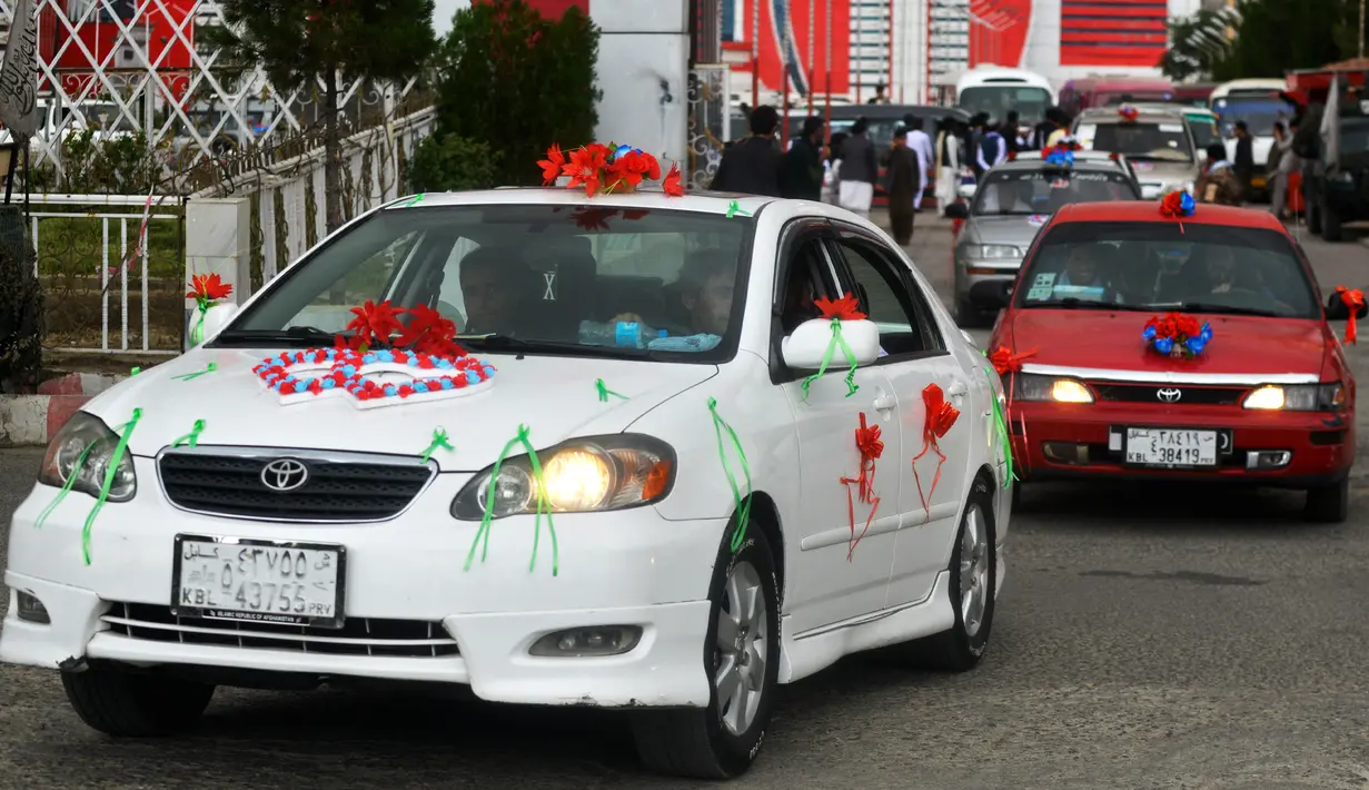 Mobil-mobil yang dihias membawa pasangan Afghanistan meninggalkan aula pernikahan setelah upacara pernikahan massal di Kabul, Afghanistan, 13 Juni 2022. (Sahel ARMAN/AFP)