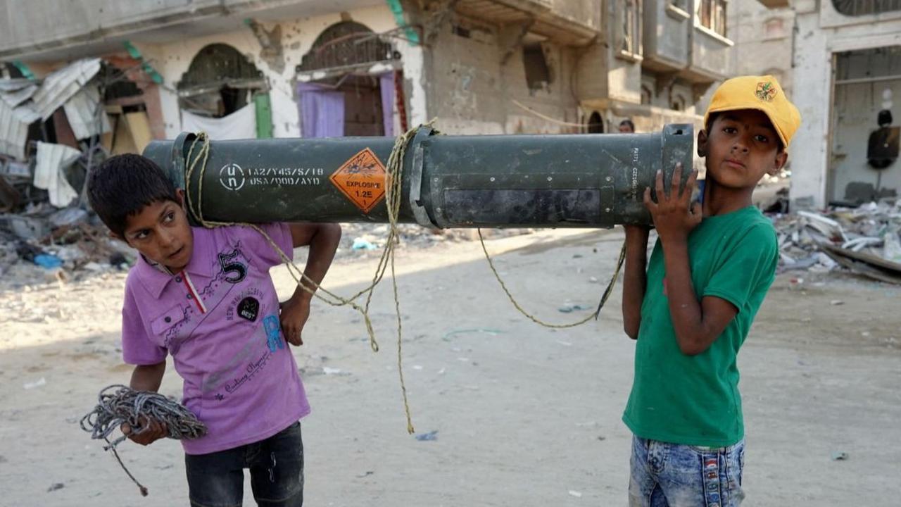 Dua orang anak mengangkat sisa amunisi Amerika Serikat di Khan Younis, Jalur Gaza selatan, pada Kamis (16/5/2024). Sisa-sisa amunisi yang telah kosong tersebut menjadi salah satu jejak serangan brutal Israel ke Jalur Gaza.&nbsp;Foto: AFP