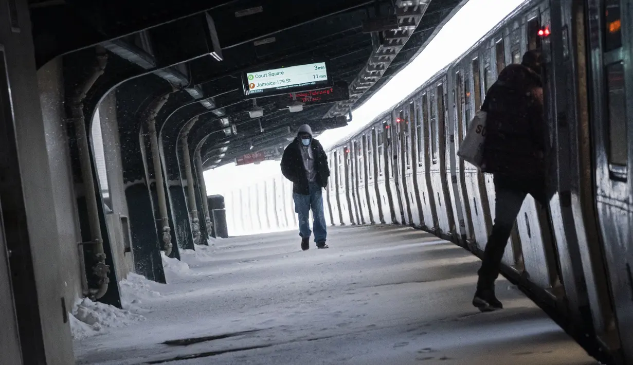 Seorang pria berjalan di sepanjang platform yang tertutup salju di stasiun kereta saat badai saljudi Brooklyn, New York, Senin, (1/2/2021). Badai salju menyebabkan timbunan salju setinggi satu kaki di sepanjang wilayah pesisir timur Amerika Serikat, termasuk Kota New York. (AP Photo/Wong Maye-E)