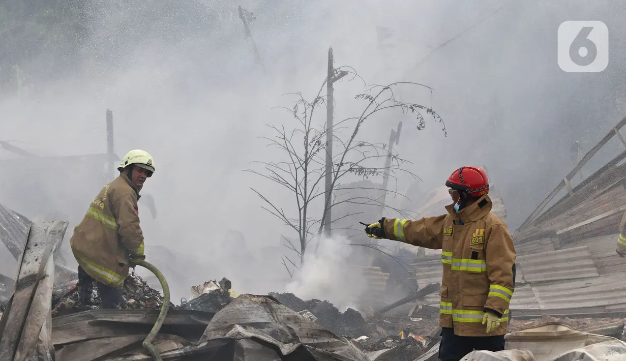 Petugas pemadam kebakaran melakukan pendingin di Pabrik penggilingan kapas,  Pasar Rebo, Jakarta Timur, Selasa (16/11/2021). Sudin Penanggulangan Kebakaran dan Penyelamatan (Gulkarmat) Jakarta Timur menurunkan 13  mobil pemadam kebakaran  untuk memadamkan api. (Liputan6.com/Herman Zakharia)
