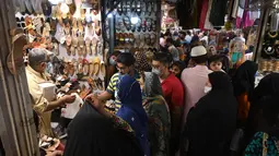Pedagang melayani pembeli di sebuah pasar di Lahore, Pakistan (4/5/2021). Di tengah pandemi virus corona Covid-19, sejumlah warga memadati area pasar tersebut menjelang hari Idul Fitri. (AFP/Arif Ali)