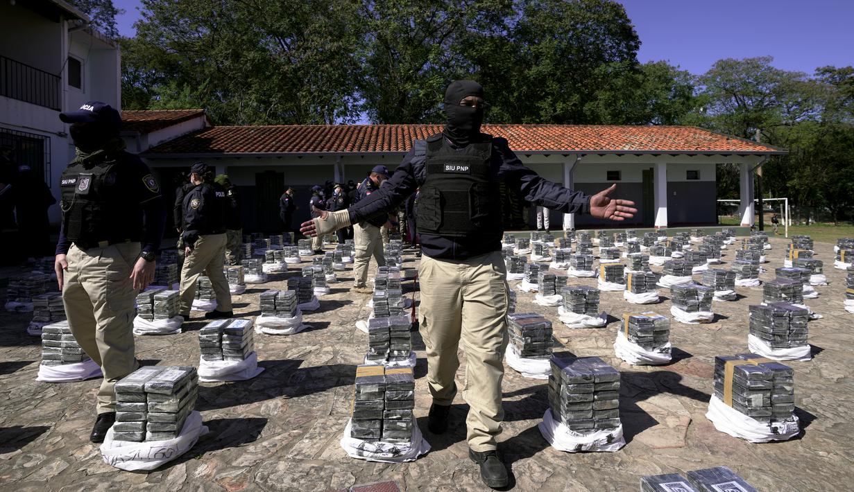 Polisi berjaga dekat kokain hasil sitaan saat diperlihatkan kepada pers di markas pasukan khusus kepolisian di Asuncion, Rabu (28/7/2021). Polisi Paraguay menyita lebih dari 3.400 kg kokain di dekat ibu kota Asuncion yang disimpan dalam muatan gula untuk pengiriman internasional. (AP/Jorge Saenz)