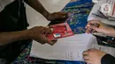 Warga menerima buku tabungan dan ATM saat mengambil Bantuan Sosial Tunai (BST) di SMAN 111, Jakarta, Selasa (19/1/2021). Pemprov DKI Jakarta menyalurkan BST sebesar Rp 300 ribu kepada 1.055.216 KK mulai Januari hingga April 2021. (Liputan6.com/Faizal Fanani)