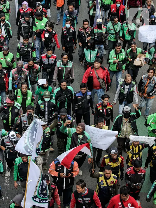 Pengemudi ojek online yang tergabung dalam Koalisi Ojol Nasional melakukan longmarch untuk menggelar aksi di depan Gedung DPR RI, Jakarta, Senin (29/8/2022). Ratusan pengemudi ojek online tersebut menuntut beberapa hal di antaranya payung hukum dan legalitas profesi ojek online serta revisi potongan komisi pendapatan mitra. (Liputan6.com/Faizal Fanani)