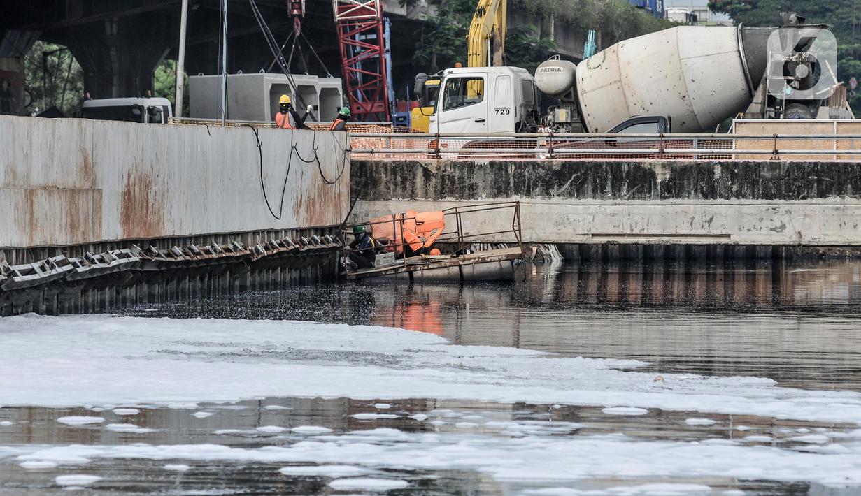Aktivitas pekerja dekat limbah busa yang mencemari Kali Ancol, Jakarta Utara, Rabu (16/3/2022). Munculnya busa tersebut diduga berasal dari limbah rumah tangga dan industri akibat belum efektifnya Instalasi Pengolahan Air Limbah (IPAL). (merdeka.com/Iqbal S. Nugroho)