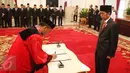 Hakim Mahkamah Konstitusi (MK) yang baru, Saldi Isra disaksikan Presiden Joko Widodo  menandatangani dokumen pelantikan sebagai Hakim MK di Istana Negara, Jakarta, Selasa (11/4). Saldi Isra menggantikan Patrialis Akbar. (Liputan6.com/Angga Yuniar)