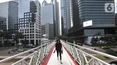 Pejalan kaki melintas di jembatan penyeberangan orang (JPO) yang tidak beratap di jalan Sudirman, Jakarta, Rabu (6/11/2019). Pemprov DKI melalui Dinas Bina Marga mencopot atap JPO Sudirman agar pejalan kaki dapat menikmati pemandangan gedung-gedung pencakar langit. (merdeka.com/Iqbal Nugroho)