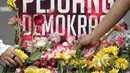 Pengunjung car free day meletakan bunga yang diberikan oleh anggota TKN Milenial Jokowi-Ma'ruf dalam kegiatan tabur bunga di Bundaran HI, Jakarta, Minggu (28/4/2019). Aksi tersebut sebagai bentuk duka atas meninggalnya 272 petugas KPPS dalam Pemilu 2019. (Liputan6.com/Faizal Fanani)