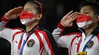 Ganda putri Indonesia Apriyani Rahayu dan Greysia Polii memberi hormat saat pemberian medali cabang badminton ganda putri Olimpiade Tokyo 2020 di Musashino Forest Sport, (2/8/2021). Greysia / Apriyani merebut emas usai menang atas pasangan China Cheng Qingchen/Jia Yi Fan. (Alexander NEMENOV/AFP)