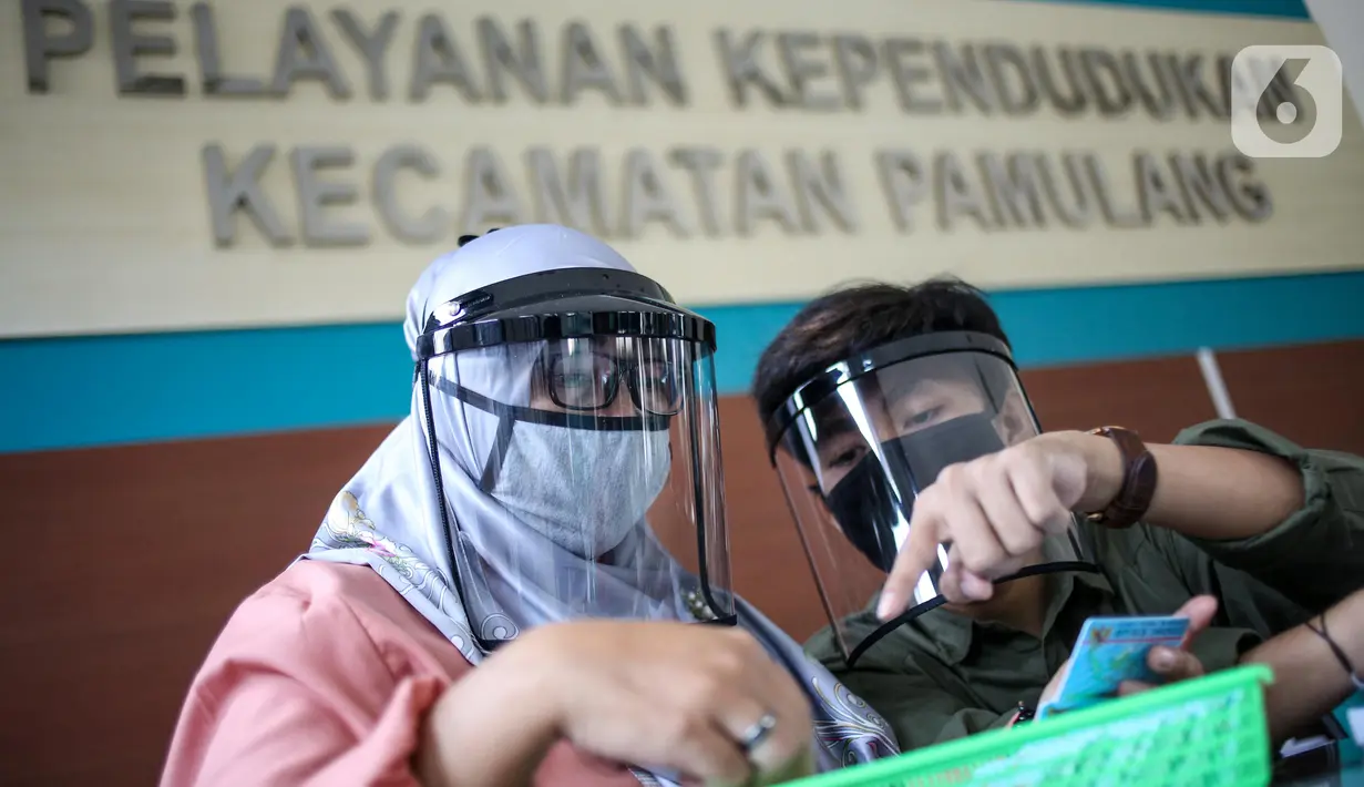 Petugas menggunakan face shield saat melayani masyarakat Dinas Kependudukan Kecamatan Pamulang, Tangerang Selatan, Jumat (29/5/2020).  Penggunaan Face Shield tersebut sebagai salah satu upaya untuk melindungi diri dalam penyebaran COVID-19. (Liputan6.com/Faizal Fanani)