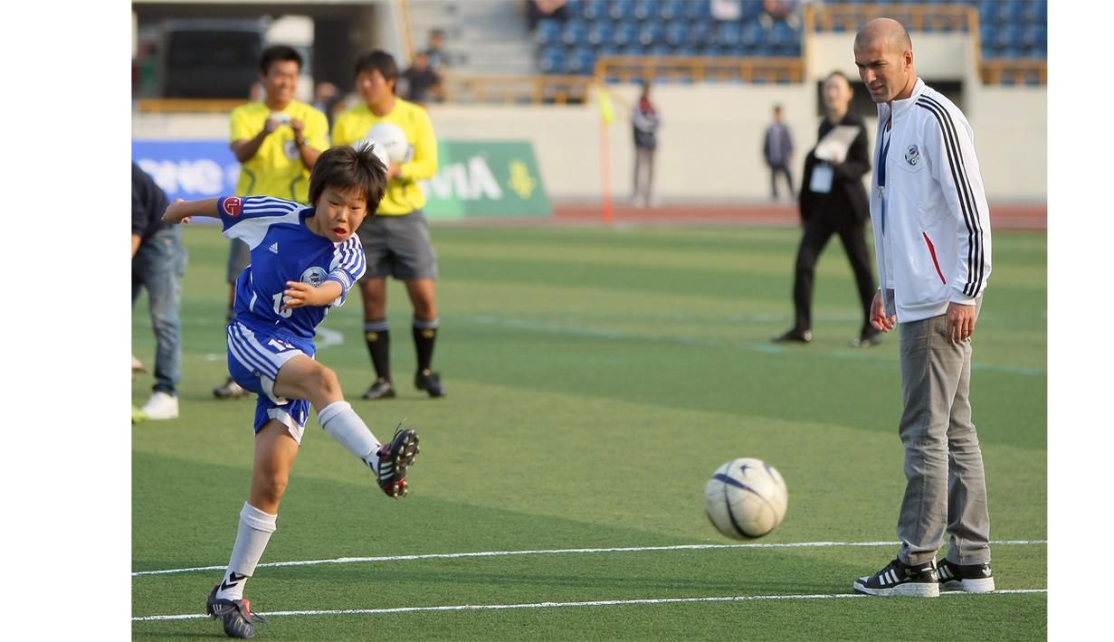  Zinedine Zidane melihat seorang anak menendang bola di Stadion Seoul, Korea Selatan, (30/10/2009). Zidane hadir sebagai duta kompetisi sepak bola Danone. (EPA/Yonhapnews Agency)