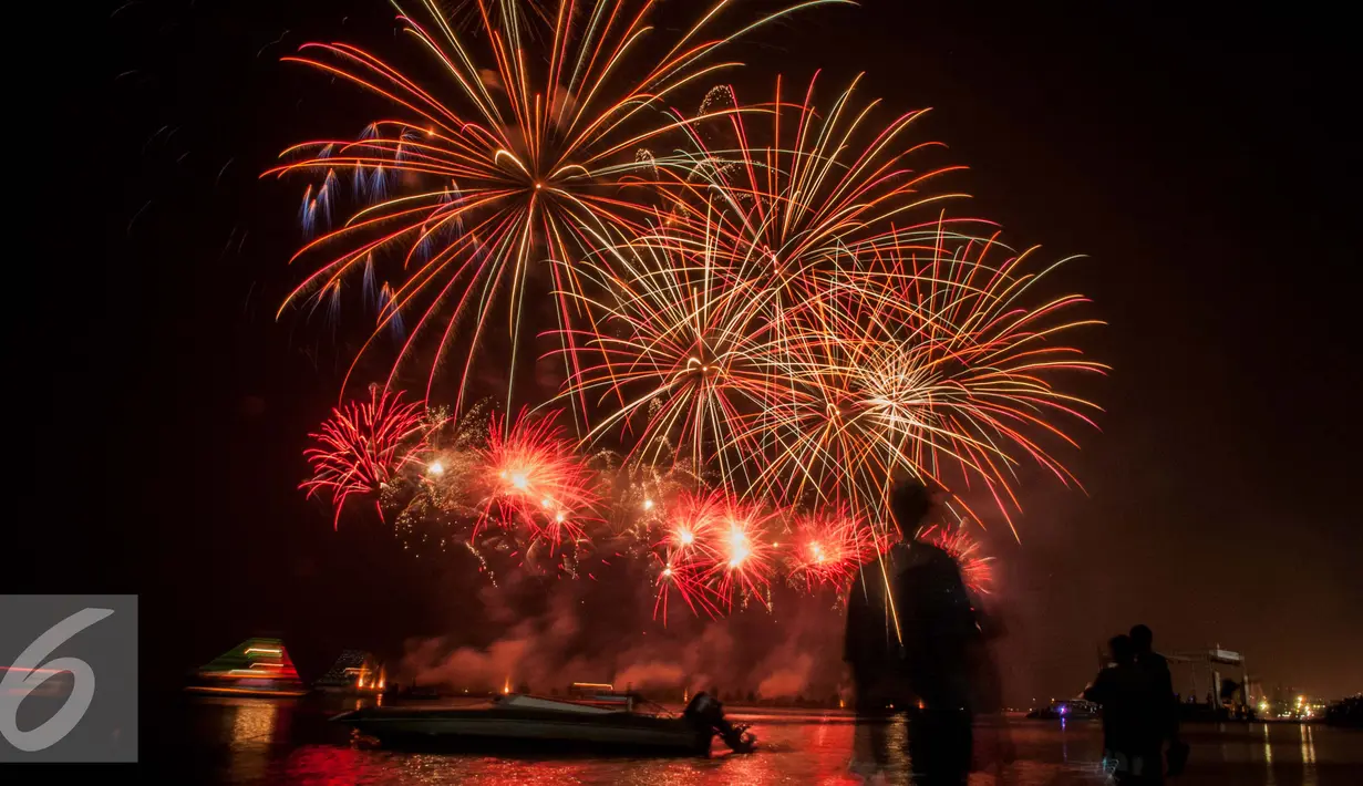 Pengunjung berfoto dengan latar belakang kembang api saat malam pergantian tahun 2017 di Pantai Lagoon, Ancol, Jakarta (1/1). Ribuan warga yang memadati kawasan tersebut tak henti-hentinya meletupkan kembang api ke udara. (Liputan6.com/Gempur M. Surya)