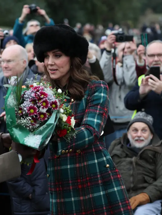 Kate Middleton menggenggam buket bunga setelah tradisi kebaktian Hari Natal Kerajaan Inggris di Gereja St. Mary Magdalene, Sandringham, Senin (25/12). Pea coat yang dipakai Kate Middleton terbuat dari bahan velvet seharga Rp 48,12 juta (AP/Alastair Grant)