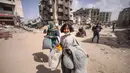 Warga Palestina mengungsi melalui jalan di dekat reruntuhan rumah yang hancur di Khan Yunis, Jalur Gaza selatan pada 6 Maret 2024. Kementerian Kesehatan Gaza mendesak institusi internasional untuk mendukung keperluan hidup, kesehatan, psikologis, dan sosial perempuan Palestina, terutama di Jalur Gaza. (Foto oleh AFP)