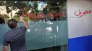 Seorang pria menyemprotkan cairan berwarna merah dan menuliskan kalimat berbahasa Arab yang artinya "Pencurian bank dan prostitusi," di jendela bank yang diserang di Beirut, Lebanon, Rabu (14/9/2022). Akibat kasus ini, muncul kasus pembobolan lain yang terjadi di bank-bank yang ada di Lebanon. (AP Photo/Hussein Malla)