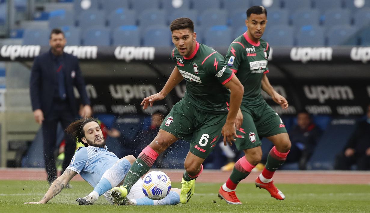 Bek Crotone, Lisandro Magallan (tengah) memenangi perebutan bola dengan gelandang Lazio, Luis Alberto dalam laga lanjutan Liga Italia 2020/2021 pekan ke-27 di Olimpico Stadium, Roma, Jumat (12/3/2021). Crotone kalah 2-3 dari Lazio. (AP/Alessandra Tarantino)