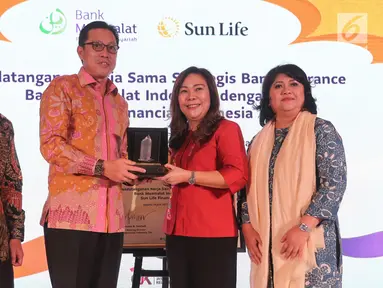 CEO Bank Muamalat Indonesia Achmad Kusna Permana dan Presdir Sun Life Financial Indonesia Elin Waty bertukar cindermata usai penandatanganan kerja sama Bancassurance, di Jakarta, Rabu (19/6). Kerjasama tersebut merupakan upaya meningkatkan layanan produk asuransi syariah. (Liputan6.com/HO/Astro)