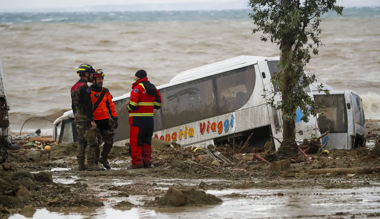Tim penyelamat berdiri di samping sebuah bus yang hanyut setelah hujan deras memicu tanah longsor yang meruntuhkan bangunan dan menyebabkan sebanyak 12 orang hilang, di Casamicciola, di pulau selatan Italia Ischia, Italia, Sabtu, 26 November 2022. (AP Photo/Salvatore Laporta)