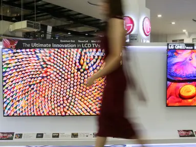 Model melintas di depan dua LG QNED Mini LED TV di toko elektronik SCBD, Jakarta, Sabtu (25/09/2021). PT LG Electronics Indonesia (LG) resmi mengumumkan TV premium, LG QNED Mini LED TV yang dikembangkan dua teknologi pada  LCD TV yaitu Quantum Dot NanoCell dan Mini LED. (Liputan6.com)
