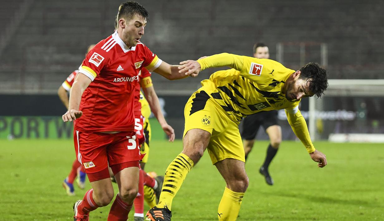 Bek Borusia Dortmund, Mats Hummels, berebut bola dengan bek Union Berlin, Robin Knoche, pada laga lanjutan Liga Jerman di Stadion Alte Forsterei, Sabtu (19/12/2020) dini hari WIB. Borussia Dortmund kalah 1-2 melawan Union Berlin. (AFP/Annegret Hilse/pool)