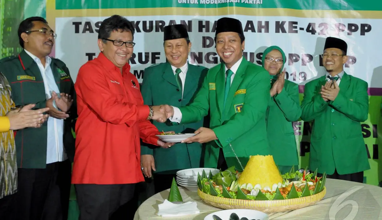 Perwakilan Partai koalisi, Hasto Kristiyanto (kiri)saat menerima potongan tumpeng dari Ketum PPP Romi (kanan), dalam acara peringatan Harlah ke-42 PPP, Jakarta, Senin (5/1/2015). (Liputan6.com/Andrian M Tunay)