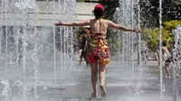 Seorang wanita menyegarkan dirinya di air mancur taman Andre Citroen, Paris, Senin (19/6). Suhu temperatur di ibu kota Prancis ini mencapai 36 derajat celcius. (AFP Photo / LUDOVIC MARIN)