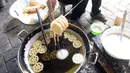 Pekerja menggoreng jajanan tradisional kembang goyang di Kelurahan Karangan, Setu, Tangerang Selatan, Banten, Kamis (6/8/2020). Jajanan kue kering berbentuk bunga tersebut dijual dengan harga Rp 5 ribu per bungkus. (merdeka.com/Dwi Narwoko)