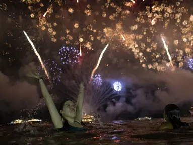 Seorang wanita menyaksikan pesta kembang api menyambut Tahun Baru 2019 di Pantai Copacabana, Rio de Janeiro, Brasil, Selasa (1/1). (AP Photo/Leo Correa)