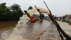 Sejumlah anak bermain di bantaran kali Ciliwung, Kampung Pulo, Jakarta Timur, Sabtu (12/3). Warga memanfaatkan lahan di aliran sungai untuk tempat bermain karena minimnya lahan kosong di sekitar wilayah itu.(Liputan6.com/Gempur M Surya)
