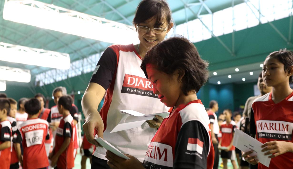 Maria Kristin, pelatih PB Djarum, membagikan amplop berisi pengumuman lolos tidaknya peserta dalam Audisi Grand Final Djarum Beasiswa Bulutangkis 2015. Minggu (6/9/2015). (Bola.com/Arief Bagus)